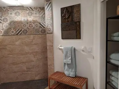 a bathroom with a shower with a towel and a wooden stool at Spacious House in Fort Lauderdale - Minutes from Beach in Fort Lauderdale