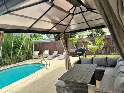 a patio with a couch and an umbrella next to a pool at Pool house 3 bedroom 2 bathroom in North Miami Beach