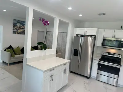 a kitchen with white cabinets and a stainless steel refrigerator at Pool house 3 bedroom 2 bathroom in North Miami Beach