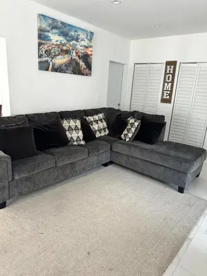 a living room with a black couch and a rug at Pool house 3 bedroom 2 bathroom in North Miami Beach