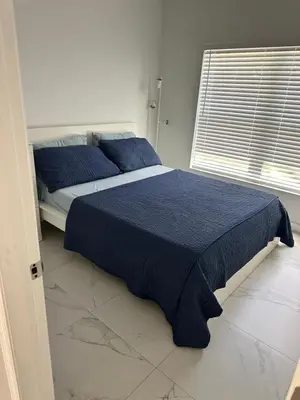 a bedroom with a bed with blue sheets and a window at Pool house 3 bedroom 2 bathroom in North Miami Beach