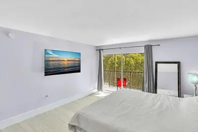 a white bedroom with a bed and a large window at One Bedroom Steps Away From The Beach! in Sunny Isles Beach