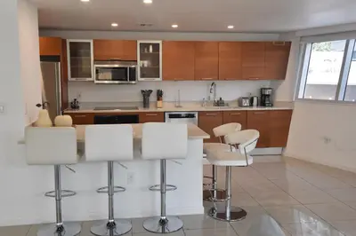 a kitchen with wooden cabinets and white stools at 515-Trendy 2Bd2Ba Midtown HUGE private patio! in Miami