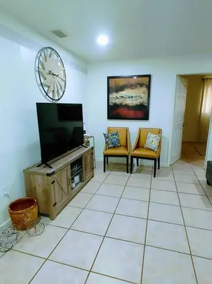 a living room with a tv and two chairs at Amazing 5 Bedroom Pool Home - Minimum 28 days Stay Only Great Location! in Miramar