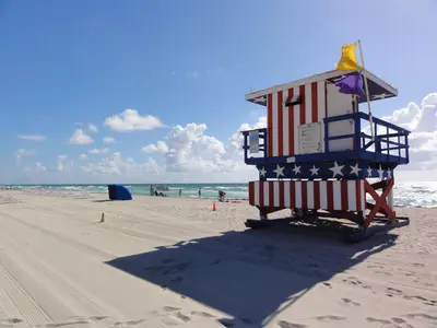 a lifeguard tower on a beach with the american flag at Seaside Serenity Duplex in Miami Beach