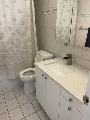 a white bathroom with a toilet and a sink at Beautiful Pavilion in Miami Beach