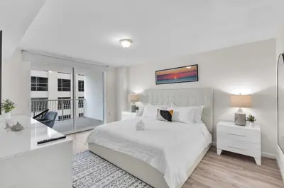 a white bedroom with a large bed and a desk at Brickell Key Gem: Stylish 1-Bed W/ Free Parking in Miami