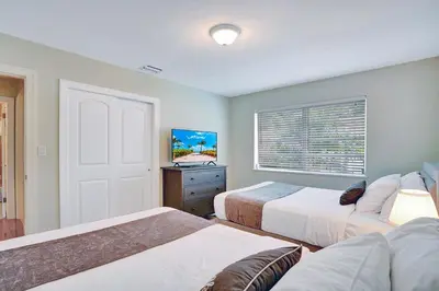 a bedroom with two beds and a tv and a window at Best Area Spacious 4BR Heated Pool Mins To Beach in Hollywood