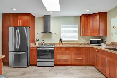 a kitchen with wooden cabinets and a stainless steel refrigerator at Best Area Spacious 4BR Heated Pool Mins To Beach in Hollywood