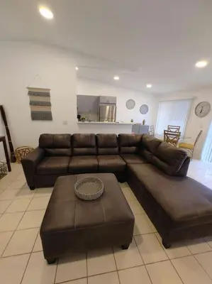 a living room with a brown leather couch and a table at Walk to Hard Rock ~ Amazing 5 Star Home Away From Home! in Miami Gardens