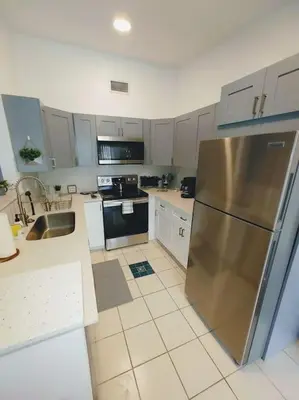 a kitchen with a stainless steel refrigerator and white cabinets at Walk to Hard Rock ~ Amazing 5 Star Home Away From Home! in Miami Gardens