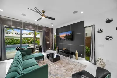a living room with a green couch and a tv at Elements Las Olas w Pool and Spa Near Beach in Fort Lauderdale