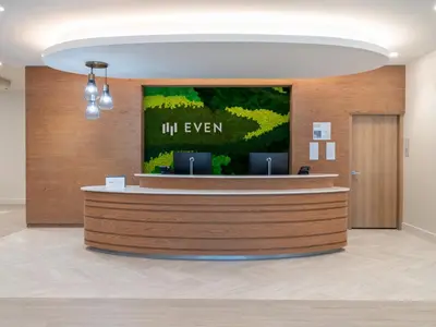 an office lobby with a reception counter with a sign at EVEN Hotel Miami - Doral Area by IHG in Sweetwater
