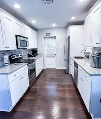 a kitchen with white cabinets and a wooden floor at Charming 4BR Home with Heated Pool in Hollywood in Hollywood