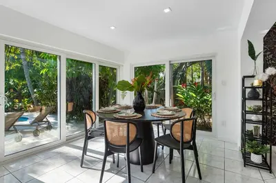 a dining room with a table and chairs and windows at The Wellness Retreat- Amazing Amenities Near Beach in Hollywood