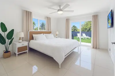 a white bedroom with a bed and a ceiling fan at Central Miami Oasis, Near Brickell, Grove & Little Havana in Miami