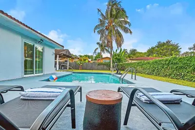 a swimming pool with chairs and a table and a house at Sunny Miami Stay - Pool - BBQ - Centrally Located in Miami