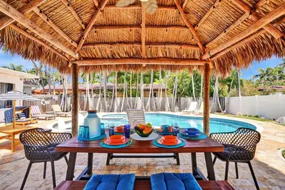 a table with plates of food sitting under a straw umbrella at Seaside Oasis in Hollywood Lakes near the Beach in Hollywood