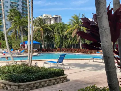 a swimming pool with two chairs and palm trees at Stunning apt! Oceanview! Parking included in Sunny Isles Beach