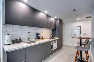 a kitchen with black cabinets and a counter top at Ocean View Designer Studio, Pool in Miami