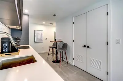 a kitchen with white cabinets and a sink and a table at Ocean View Designer Studio, Pool in Miami