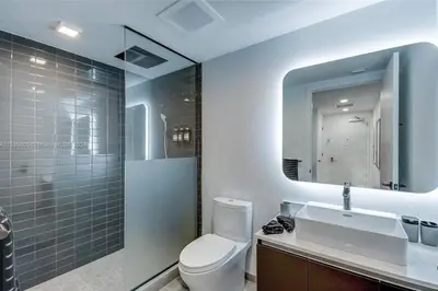 a bathroom with a toilet and a sink and a mirror at Ocean View Designer Studio, Pool in Miami