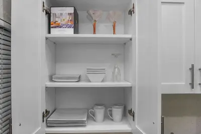 a white cabinet with plates and cups and dishes at Miami Luxury Home Rental in Miami