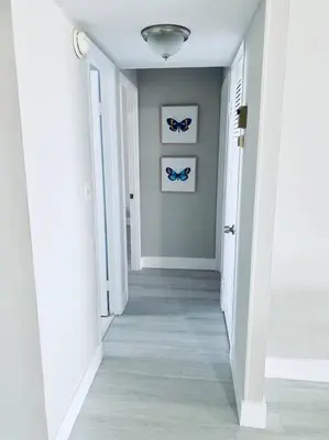 a hallway with white walls and blue butterflies on the wall at MODERN 2BR 2BA CONDO near AVENTURA! Wi-Fi! Parking in North Miami Beach