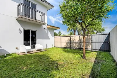 a yard with two white chairs and a tree at Biscayne Park Villas 15400 in Miami