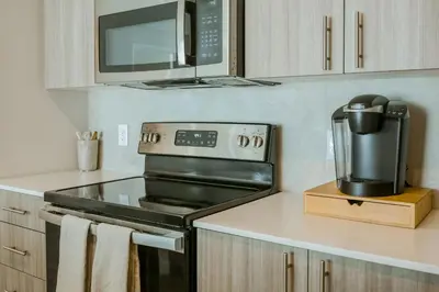 a kitchen with a stove and a microwave at 1 Mi to Hard Rock Stadium! Chic Retreat with Pool in Joe Robbie Stadium Heliport