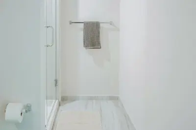 a white bathroom with a shower with a towel at 1 Mi to Hard Rock Stadium! Chic Retreat with Pool in Joe Robbie Stadium Heliport