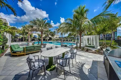 a patio with a table and chairs and a pool at 1 Mi to Hard Rock Stadium! Chic Retreat with Pool in Joe Robbie Stadium Heliport