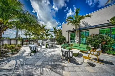 a patio with furniture and tables and palm trees at 1 Mi to Hard Rock Stadium! Chic Retreat with Pool in Joe Robbie Stadium Heliport