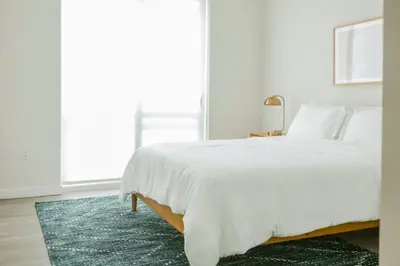 a bedroom with a white bed and a green rug at Hard Rock Stadium Home Base! Luxe Condo with Pool in Joe Robbie Stadium Heliport