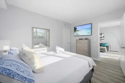 a white bedroom with a bed and a dresser at Beautiful holiday apartment in Ocean Recerve near beach in Sunny Isles Beach