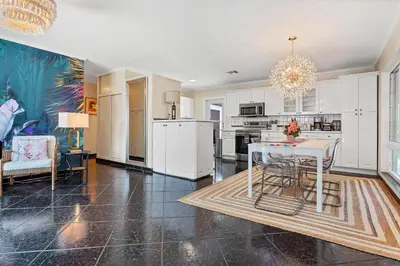 a kitchen with white cabinets and a table and chairs at 5 Minute Walk to Wilton Drive in Fort Lauderdale