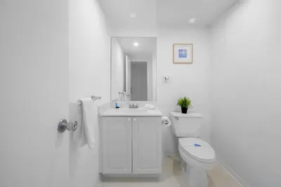 a white bathroom with a toilet and a sink at Nice and economic family apartment on the beach in Sunny Isles Beach