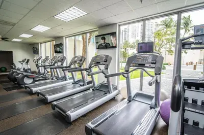 a gym with rows of tread machines in a room at Nice and economic family apartment on the beach in Sunny Isles Beach