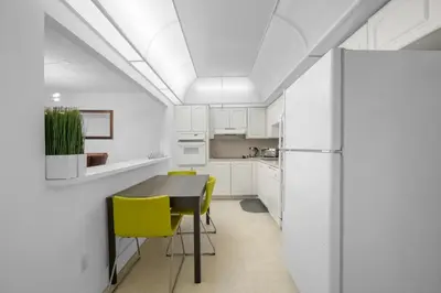 a kitchen with white cabinets and a table and yellow chairs at Nice and economic family apartment on the beach in Sunny Isles Beach