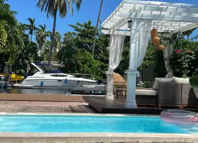 a white pergola and a swimming pool with a boat at D' Mauchi Waterfront House in Miami