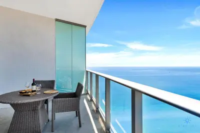 a balcony with a table and chairs and the ocean at Hollywood Beachfront Apt Amazing View & Amenities in Hollywood