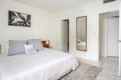 a white bedroom with a large bed and a mirror at Beachfront, Pools, Patio, King Bd Villa- Hollywood FL in Hollywood