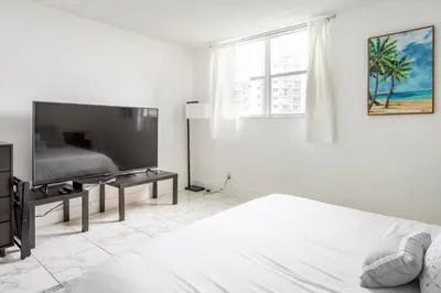 a white bedroom with a bed and a flat screen tv at Beachfront, Pools, Patio, King Bd Villa- Hollywood FL in Hollywood