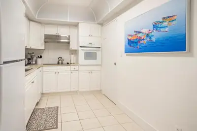 a kitchen with white cabinets and a painting on the wall at Beachfront, Pools, Patio, King Bd Villa- Hollywood FL in Hollywood