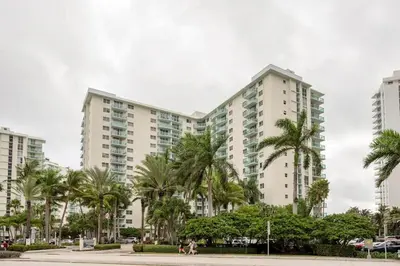 a group of tall white buildings with palm trees at Beachfront, Pools, Patio, King Bd Villa- Hollywood FL in Hollywood