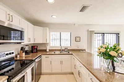 a kitchen with white cabinets and a vase of flowers at Miami Oasis 7 mins to Dolphin Mall MIA PS4 Games in Miami