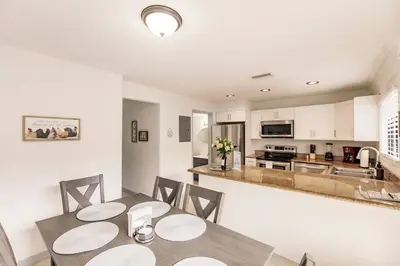 a dining room with a table and chairs and a kitchen at Miami Oasis 7 mins to Dolphin Mall MIA PS4 Games in Miami