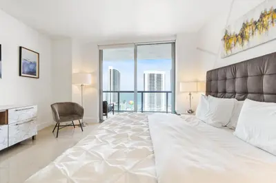 a bedroom with a large white bed with a large window at Spacious Luxury Apartment at Beachwalk Resort with Ocean Views and Private Foyer in Hallandale Beach