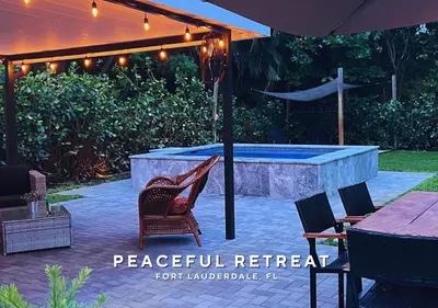 a patio with a pool and chairs and an umbrella at Private Heated Plunge Pool Spa and Secluded Patio - Fort Lauderdale in Fort Lauderdale