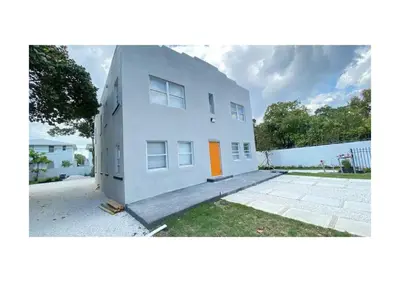 a white building with an orange door on it at Cozy Duplex near Wynwood & Beach in Miami